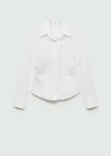 Camisa blanca de popelina de algodón con cuello camisero, cierre de botones, manga larga y detalles fruncidos.