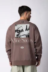 Buzo de cuello redondo y corte oversize, confeccionado en frisa suave. Presenta un diseño minimalista en color negro con un pequeño logo ovalado en el centro del pecho y una estampa sutil en el lateral inferior derecho.