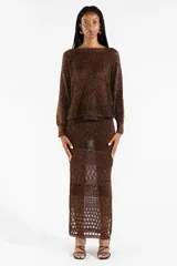 Falda midi tejida con diseño calado y abertura frontal, color marrón con hilos metalizados dorados.