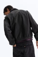 Campera negra de tejido revestido con cuello, cierre frontal y bolsillos laterales. Cuenta con puños y bajo con elástico revestido.
