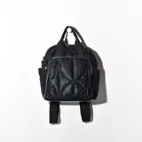 Mochila negra acolchada con diseño de rombos. Tiene un asa corta superior, dos correas traseras ajustables, un bolsillo frontal con cierre y dos bolsillos laterales abiertos.