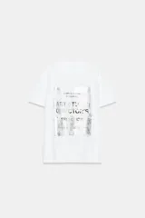 Camiseta de algodón con cuello redondo y manga corta. Presenta un diseño estampado frontal con efecto metalizado plateado sobre fondo rectangular.