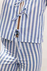 Pantalón celeste y blanco a rayas verticales, de tiro medio, corte recto y bolsillos traseros.