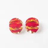 Caravanas circulares de diseño estructurado, compuestas por capas alternas de metal dorado y tela roja plisada.