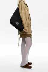 Bolso shopper de estructura blanda y gran tamaño, confeccionado en tejido técnico tipo mesh. Cuenta con doble asa de hombro, cierre mediante cordón ajustable y etiqueta de cuero con logo grabado en la parte frontal.