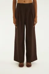 Pantalón sastrero de tiro alto y pierna ancha, color marrón con sutiles rayas diplomáticas. Presenta pinzas en la parte delantera y presillas para cinto.