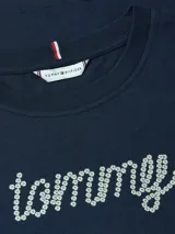 Remera de manga corta, cuello redondo, color azul marino. Presenta el logo 'tommy' estampado en la parte frontal con pedrería blanca (strass) que simula flores.