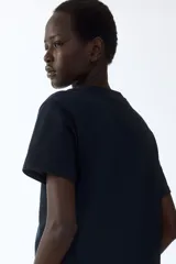 Remera de corte recto en punto suave de algodón, con cuello redondo ribeteado y hombros ligeramente caídos.
