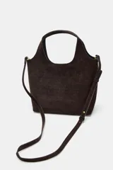 Bolso formato mini shopper confeccionado en piel de ante color topo. Cuenta con doble asa de mano, asa bandolera extraíble, cierre mediante botón imantado y bolsillo interior con cremallera.