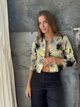 Blazer corto con estampado abstracto en tonos dorados, negros y grises. Tiene mangas 3/4 y corte recto.