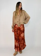 Pollera midi de corte al bies con estampado tie-dye en tonos rojizos y marrones. Confeccionada en tela fluida con caída suave.