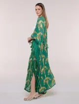 Kimono largo de viscosa color verde con estampado metalizado dorado de palmeras, mangas anchas, detalles de pompones en los bordes y diseño abierto.
