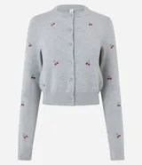 Cardigan corto de punto color gris, con cuello redondo, mangas largas y cierre frontal con botones. Presenta un diseño ajustado al cuerpo con bordados de cerezas distribuidos por toda la prenda.