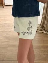 Short elastizado color marfil con delicados bordados de flores en tono azul marino en la parte frontal.