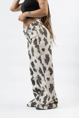 Pantalón wide leg con estampado de vaca en blanco y negro, de tiro alto y cierre de botón y cremallera.