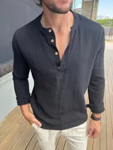Camisa de manga larga confeccionada en muselina de algodón, color negro, con cuello mao y cierre frontal parcial con botones de madera.
