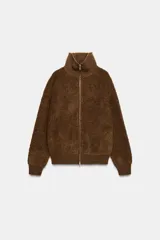 Chaqueta estilo bomber de lana bouclé color marrón, con cuello alto, cierre frontal con cremallera y puños y ruedo en tejido rib.