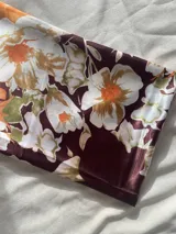 Pañuelo cuadrado de seda con estampado floral en tonos naranja, borra de vino, beige y blanco.