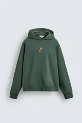 Sudadera con capucha de corte relajado, color verde oscuro, con interior perchado y bordado pequeño de una silla en el centro del pecho.