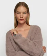 Sweater de punto oversize color marrón, con cuello en V y confeccionado en una mezcla de lana de alpaca. Presenta ribetes anchos en cuello, puños y bajo, con un diseño de hombros caídos y textura suave.