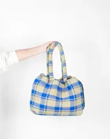 Bolso tipo tote bag de franela a cuadros en tonos azul y beige, con asas tubulares acolchadas y cierre con cordón ajustable.