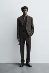 Pantalón de traje regular fit confeccionado en tejido de lana. Presenta bolsillos frontales, bolsillos traseros de vivo con botón y cierre frontal con cremallera y botón.