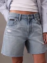 Short de jean de tiro alto con diseño de cinco bolsillos, cierre de cremallera y botón, con detalles de roturas y ruedo deshilachado.