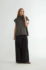 Chaleco de punto gris con cuello alto, diseño sin mangas y corte holgado.
