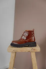 Borcego de cuero color suela con puntera redondeada, cierre mediante tiras de velcro y suela track de goma negra.