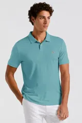 Remera polo de manga corta color turquesa, con cuello clásico, cierre frontal de dos botones y el logo del pingüino bordado en el pecho.