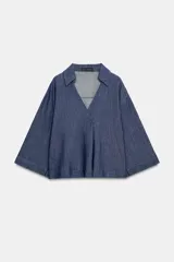 Camisa de lino azul, con cuello solapa, escote en V y mangas por debajo del codo.