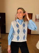 Chaleco de punto con diseño de rombos en tonos crema y azul, cuello en V y terminaciones acanaladas.