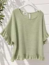 Blusa verde claro con textura arrugada, de corte holgado y mangas cortas con volados. Presenta cuello redondo y detalle de abertura con botón en la parte superior trasera, además de un sutil volado en el ruedo.