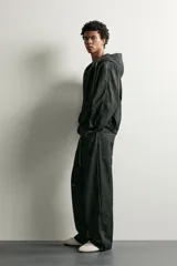 Jeans wide fit de denim negro, con costuras y detalles en color verde claro, bolsillos laterales y traseros, y cintura ajustable con cordón integrado.