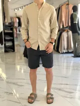Camisa de lino color beige, de manga larga con puños arremangados y cuello mao. Cuenta con cierre frontal de botones y diseño clásico.