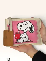 Sobre de cuero marrón con diseño pintado a mano que presenta al personaje Snoopy sobre un fondo rosado y la palabra 'heal'. Cuenta con cierre superior y etiqueta de cuero colgante.