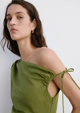 Vestido midi verde militar de corte slim, confeccionado en mezcla de lino y lyocell. Presenta diseño asimétrico de un solo hombro con manga corta y detalle de cordón ajustable, pliegues fruncidos en el lateral y tajo en el borde inferior.