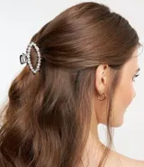 Pinza para el pelo plateada con forma ovalada y detalle de perlas artificiales.