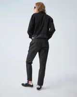 Pantalón negro de corte slim, confeccionado en lana y poliéster con elastano. Presenta cintura elastizada, cierre frontal con snap metálico, bolsillos laterales con cierre metálico y cierre en la botamanga.