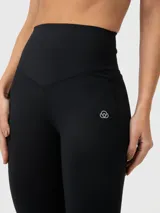 Calza deportiva de tiro alto con diseño flare, confeccionada en tejido elástico de compresión. Presenta una banda ancha en la cintura para mayor soporte y logo pequeño en la cadera.
