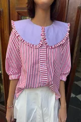 Camisa de mangas 3/4 abullonadas con cuello bebé removible, a rayas verticales rojas y blancas.