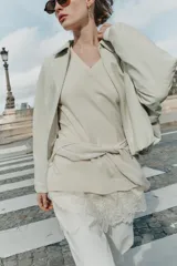 Chaqueta estilo bomber de cuero sintético en color beige, con cuello solapa, cierre frontal con cremallera, mangas largas y bajo elástico fruncido.