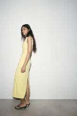 Vestido midi de cuello subido y sin mangas, confeccionado con un diseño drapeado lateral que aporta textura y movimiento a la prenda. Presenta un corte entallado y cierre de cremallera oculta en la espalda.