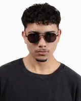 Lentes de sol con marco octogonal de metal negro y lentes oscuros.