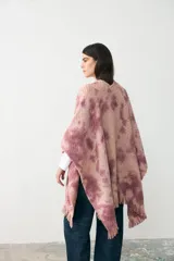 Ruana de tejido de punto con diseño teñido artesanalmente en tonos rosados y beige, con terminación de flecos en el ruedo.