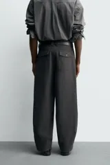 Pantalón de corte balloon fit, color negro, con bolsillos laterales de vivo y bolsillos traseros con solapa. Presenta cierre frontal con cremallera y botón.