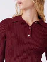 Buzo de tejido acanalado marca Rio & Rian, color beige, con cuello tipo polo con solapa y botones frontales, y mangas tres cuartos.