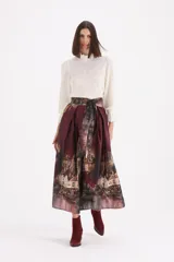 Falda midi de corte acampanado con estampado artístico de paisaje urbano. Presenta cintura alta con lazo ajustable del mismo tejido y diseño estructurado con pliegues.