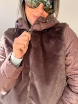 Campera con cuerpo de piel sintética tipo teddy y mangas acolchadas. Presenta cierre frontal, capucha y diseño de corte recto.