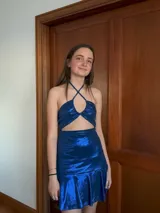 Vestido corto con estampado de rayas horizontales en tonos grises y negros. Diseño con escote halter que se ata al cuello, abertura central en el busto y falda corta con volado.